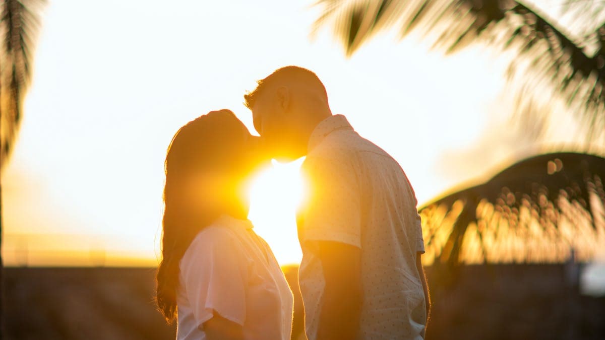 Silhouettes of a couple kissing on a tropical beach at sunset in Maui, Hawaii