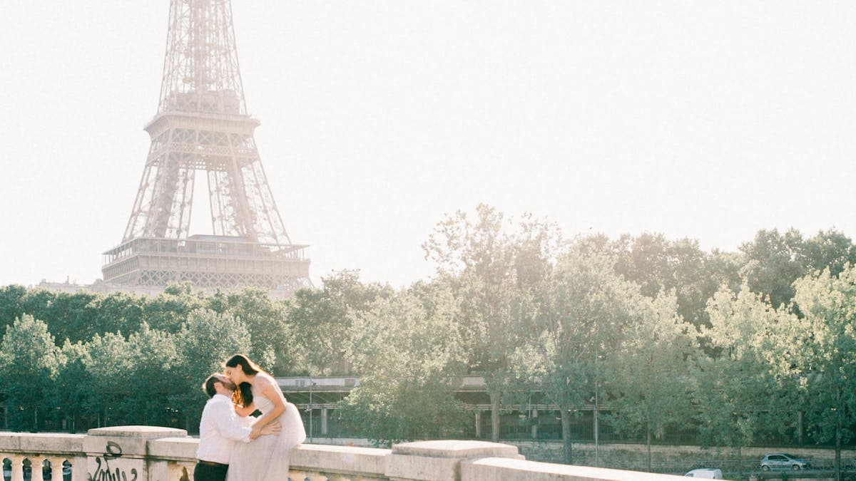 Romantic couple kissing on a bridge overlooking the Eiffel Tower in Paris, France