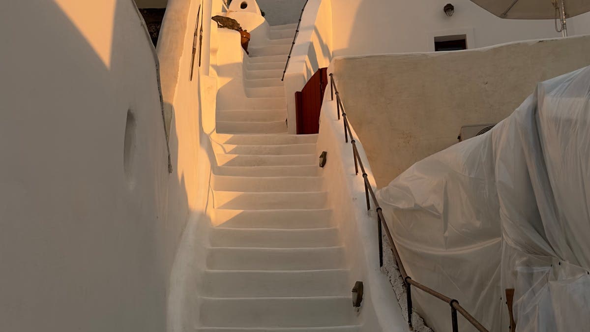 Charming whitewashed stairs bathed in golden sunset light in Santorini, Greece