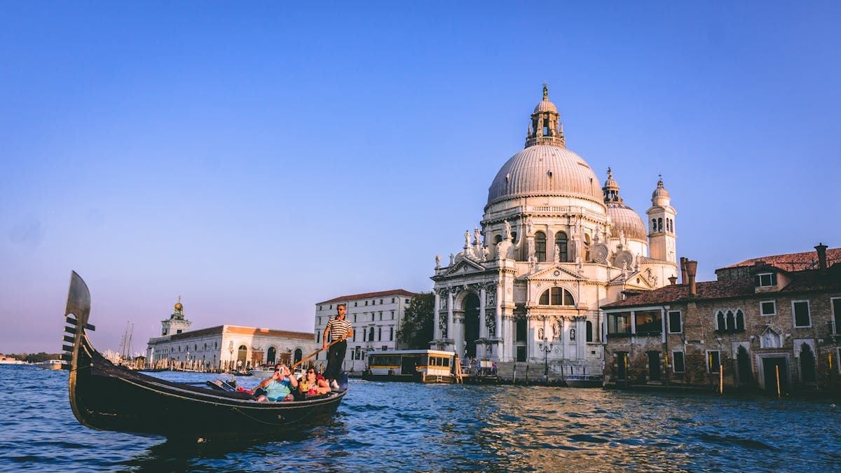 Couple riding a gondola along Venice's iconic canals with historic architecture in the background